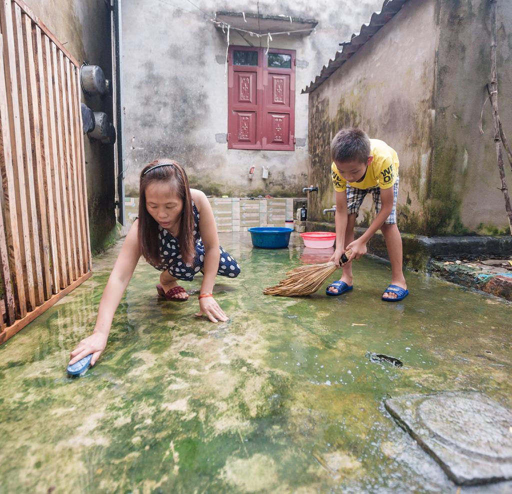 Chị Minh, công nhân may và con trai Tuấn Anh cọ rửa sân nhà.